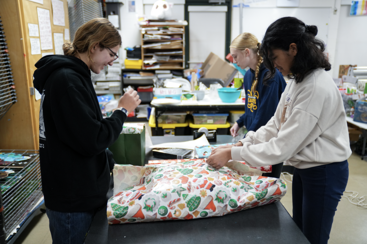 Middle schoolers wrap presents for Builders Club's annual adopt-a-family charity drive.